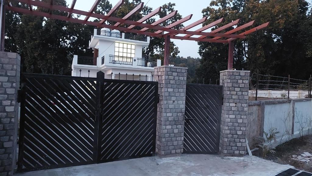 einen schwarzen Zaun mit einem Tor und einer Pergola in der Unterkunft PRITHVI FOREST HOMESTAY in Dehradun