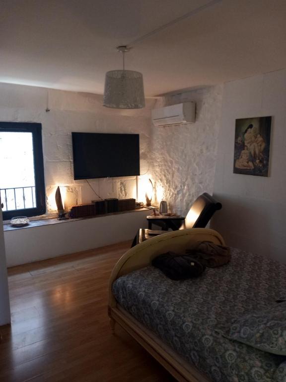 une chambre avec un lit et une télévision à écran plat dans l'établissement La P'tite Maison, à Jonquières-et-Saint-Vincent