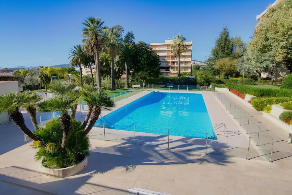 a swimming pool with palm trees and a building at Studio résidence de Standing Piscine proche plage in Antibes