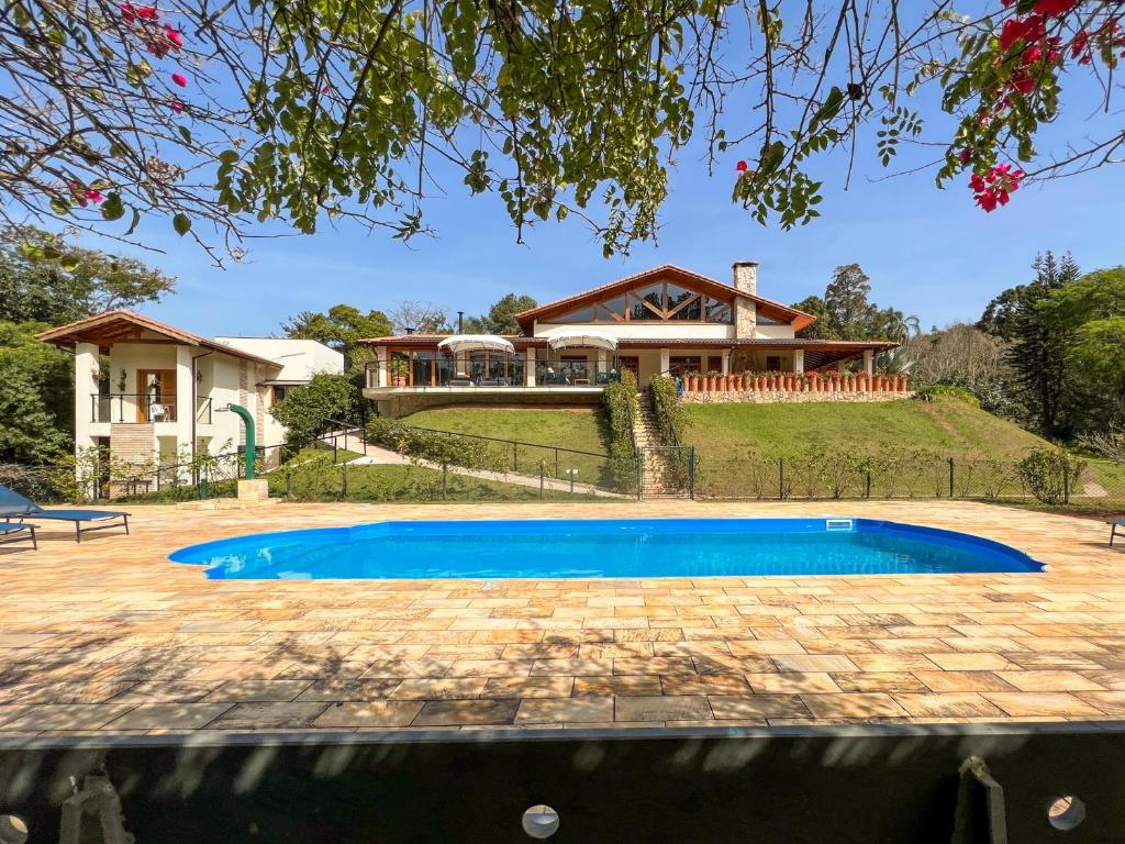 a house with a swimming pool in front of a house at Pousada Gardenian in São Roque