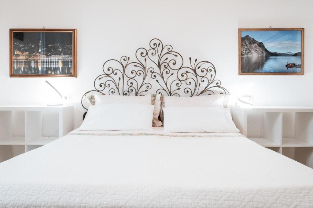 a white bedroom with a white bed with a large headboard at Casa Imbarcadero in Lecco