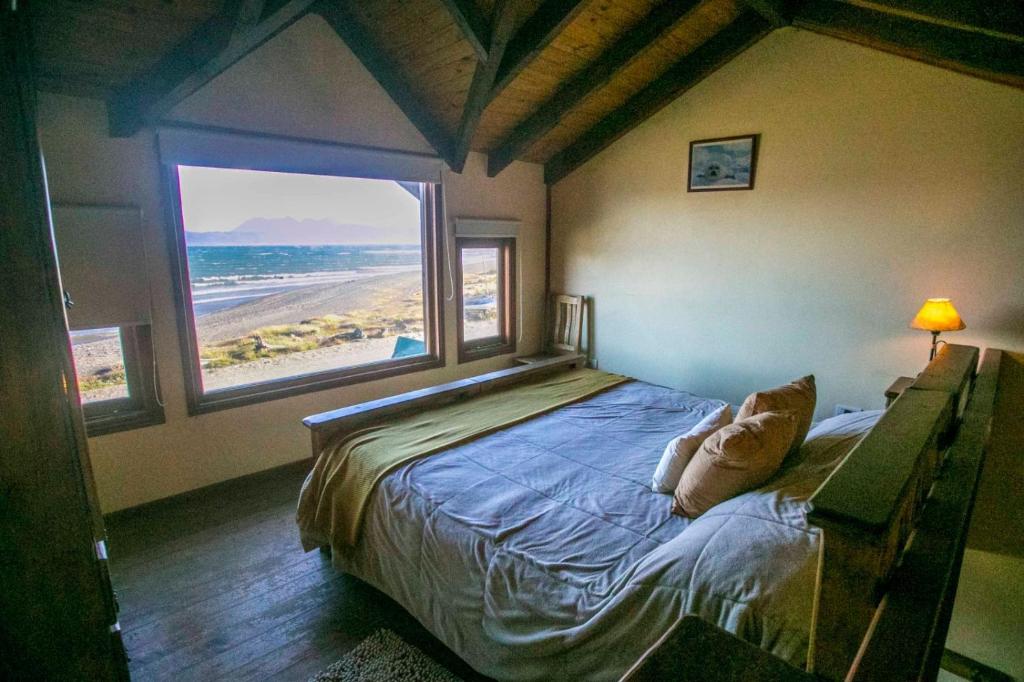a bedroom with a bed with a view of the beach at Bosque Del Sur Cabañas in Ushuaia