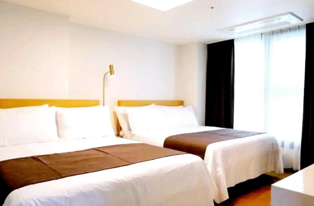 um quarto de hotel com duas camas e uma janela em Ciel de Mer em Busan