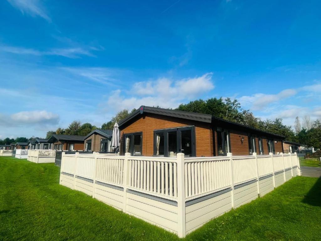 a house with a white fence in the grass at Rosie's Rest With Hot Tub in Barmby on the Moor