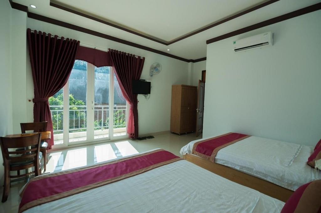 a bedroom with two beds and a window with a balcony at Lak View hotel in Lien Son