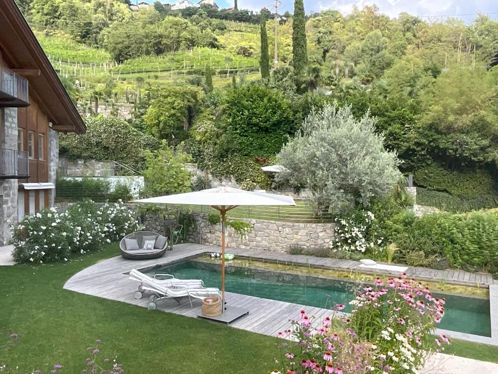 einen Pool mit einem Sonnenschirm, 2 Stühlen und einem Tisch in der Unterkunft Villa Tschaupp in Dorf Tirol