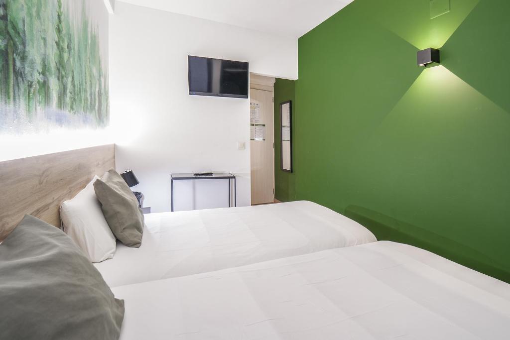 2 camas en una habitación con una pared verde en Glaner Hotel Cafe, en Andorra la Vella