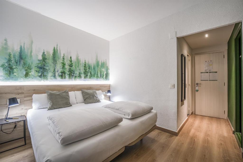 a bedroom with a bed and a window with trees at Glaner Hotel Cafe in Andorra la Vella