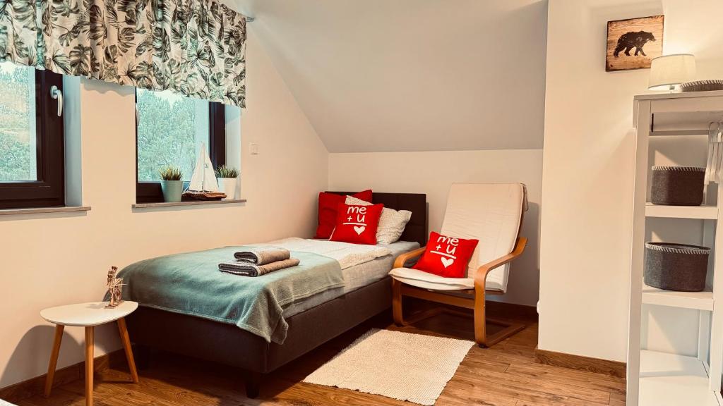 een slaapkamer met een bed met rode kussens en een stoel bij Morze Las Domki nad morzem Rozewie in Rozewie