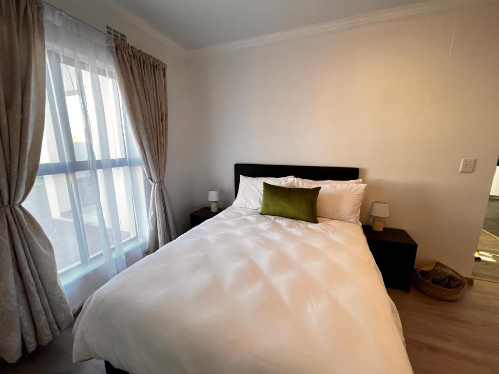 a bedroom with a white bed with a green pillow at 2nd on Strand in Cape Town
