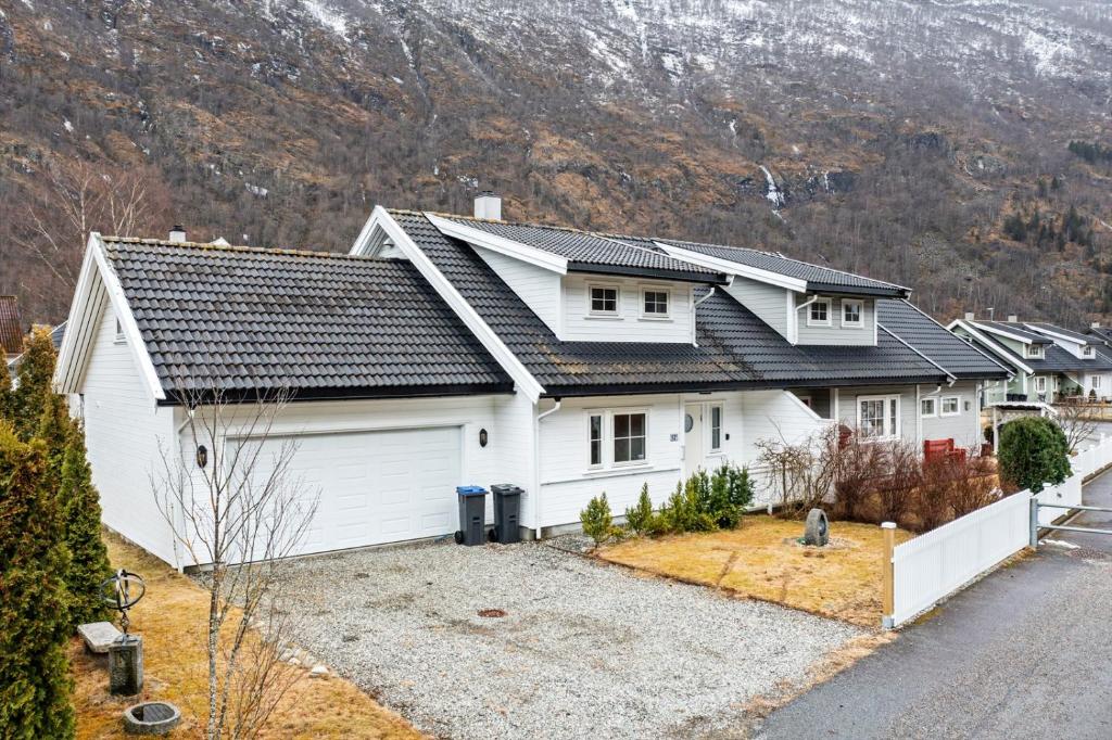 una casa blanca con una montaña en el fondo en Bjørn og Jasmins plass, en Lærdalsøyri