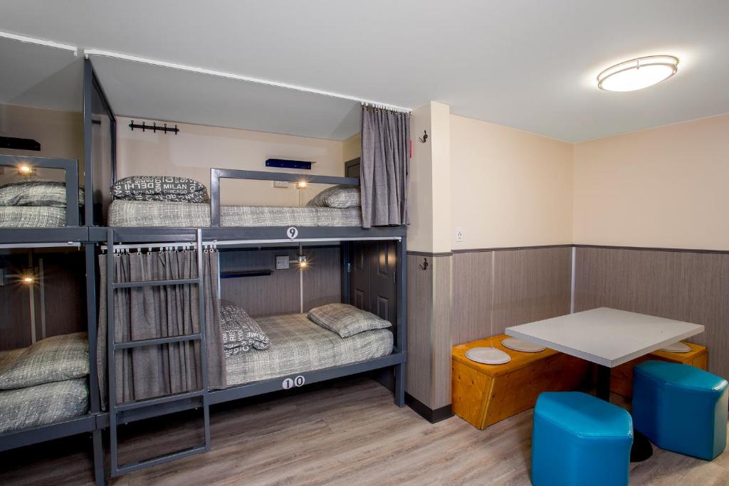 a room with bunk beds with a table and chairs at Jasper Downtown Hostel in Jasper