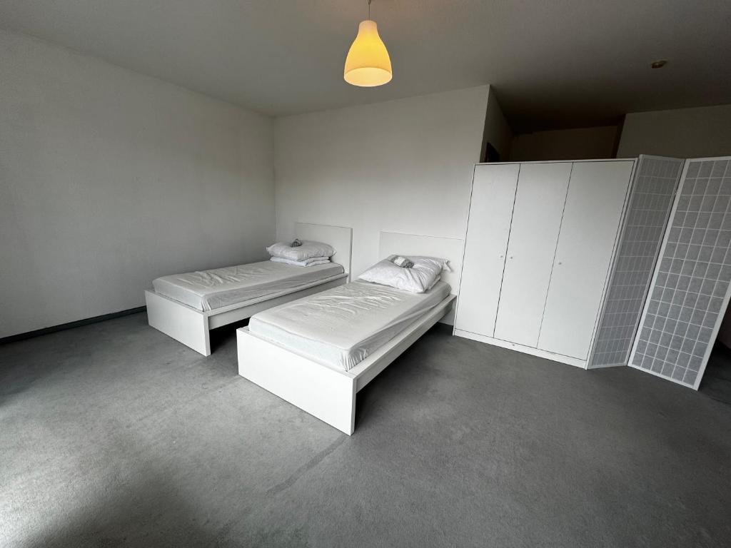 - 2 lits dans une chambre aux murs blancs dans l'établissement Apartkeep Magdeburg 36, à Magdebourg