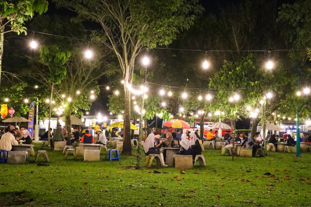 een groep mensen die 's nachts aan tafel in een park zitten bij Relax Spot View @ Meru Raya in Ipoh