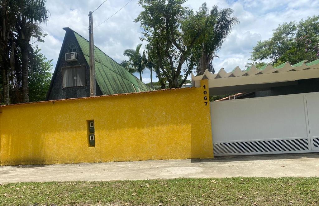 une maison avec un mur jaune et un garage blanc dans l'établissement Chales Guarau, à Peruíbe