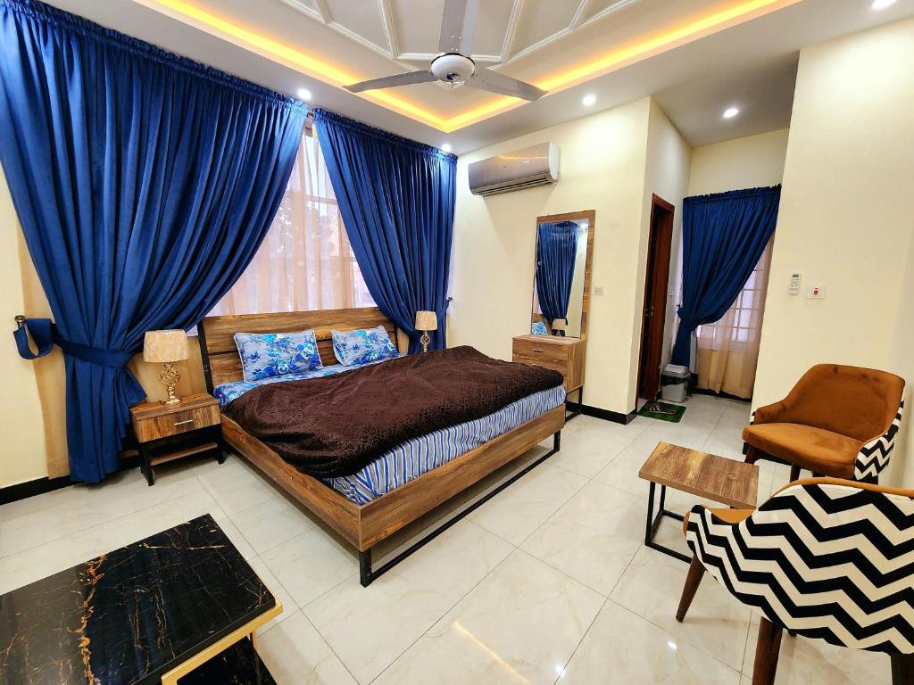 a bedroom with a bed and blue drapes at Motorway Majesty Lodges - Near Islamabad International Airport & Motorway in Islamabad
