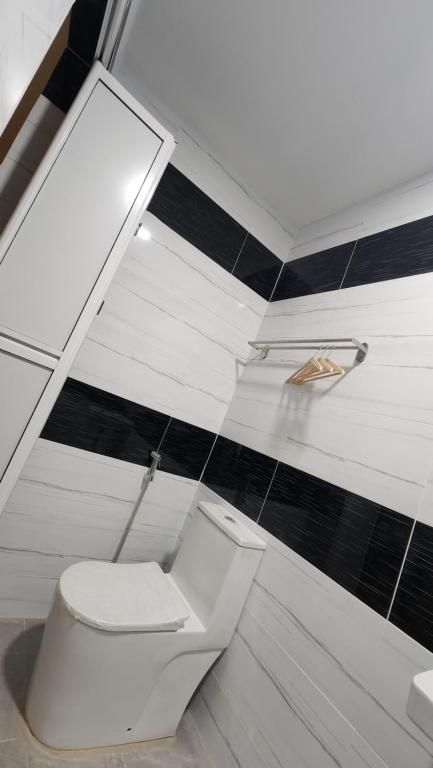 a bathroom with a white toilet and black tiles at DUSUN TOK SYED, ECOTHERAPY VILLAGE in Pendang