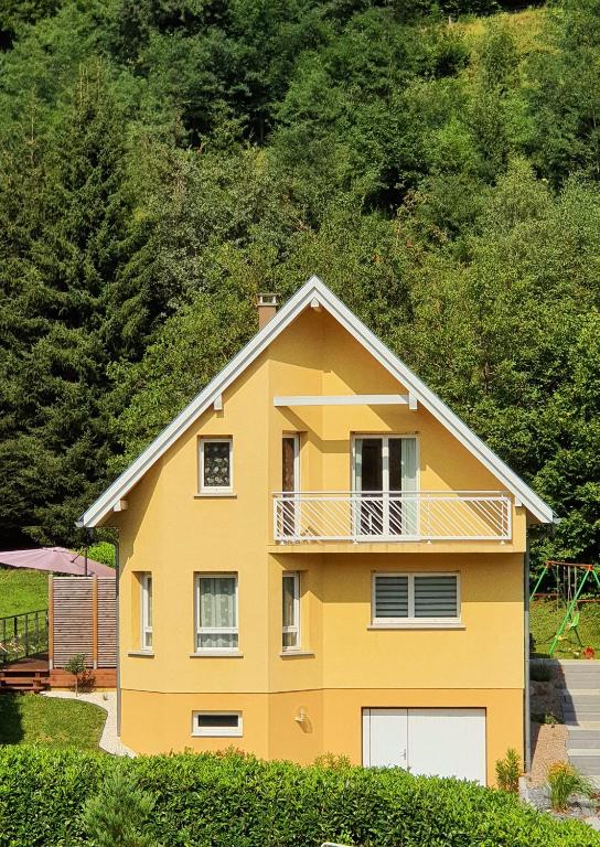 Cette maison jaune dispose d'un balcon. dans l'établissement Adossée à la colline, à Willer-sur-Thur