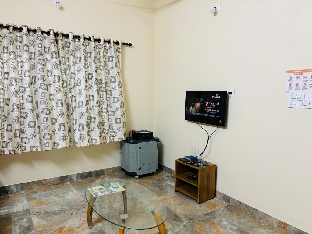 a room with a tv and a table and a curtain at Friendly homestay in Mangalore-Greenview in Kankanādi