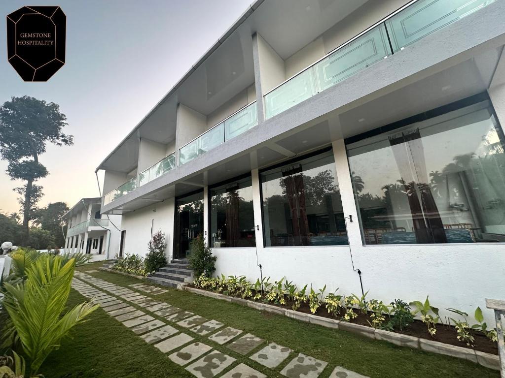 a white building with large windows and plants at Golden Pearl Resort By Gemstone Hospitality in Alibag