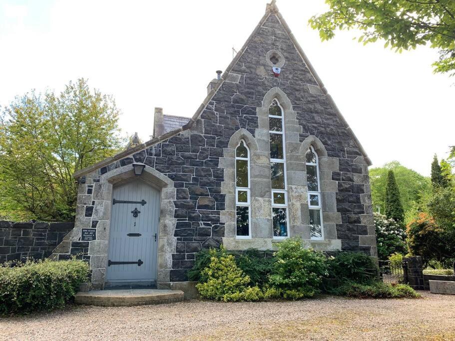 uma pequena igreja de pedra com uma porta azul em Old Schoolhouse, Galgorm (Annexe) em Galgorm