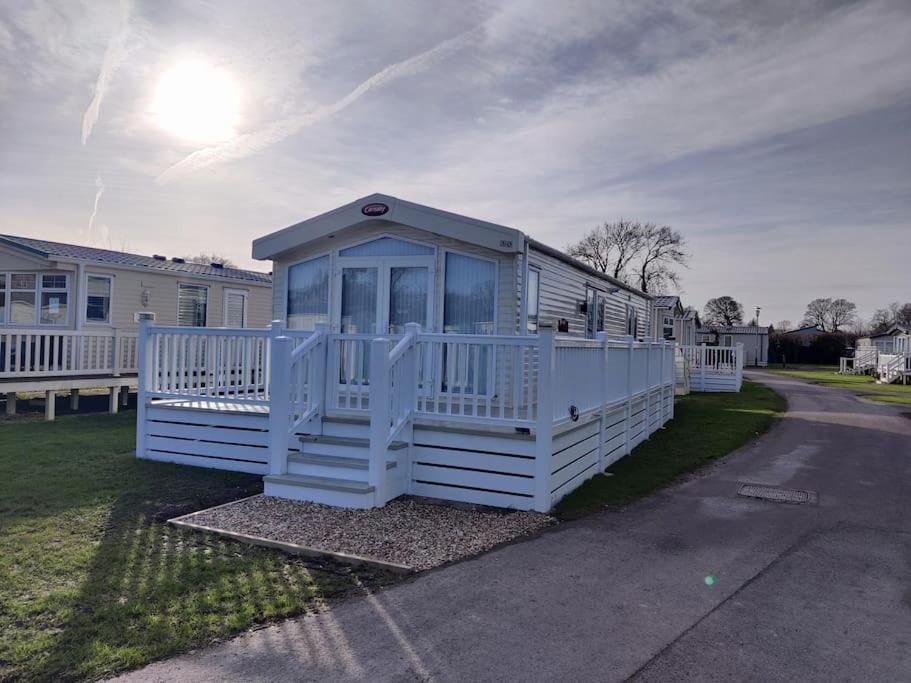 a white mobile home with a porch on a street at Forest Getaway, sleeps 6 at Bashley, leisure PASS included in New Milton