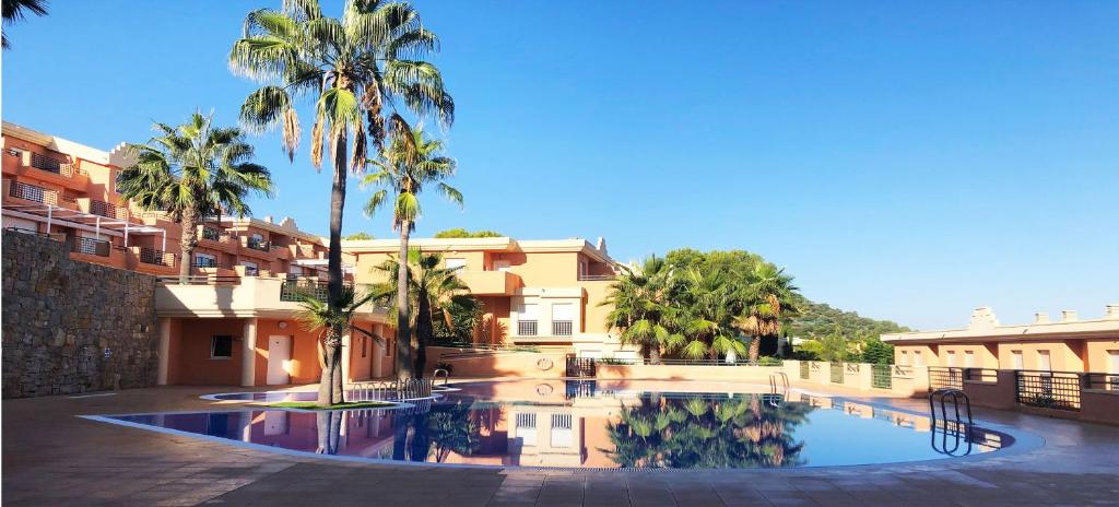 a swimming pool with palm trees in front of a building at Appartement Mar y golf in Pedreguer