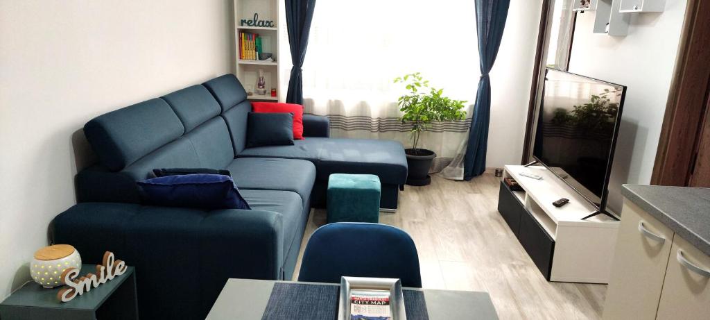ein Wohnzimmer mit einem blauen Sofa und einem TV in der Unterkunft LittleBIG Apartment in Bukarest