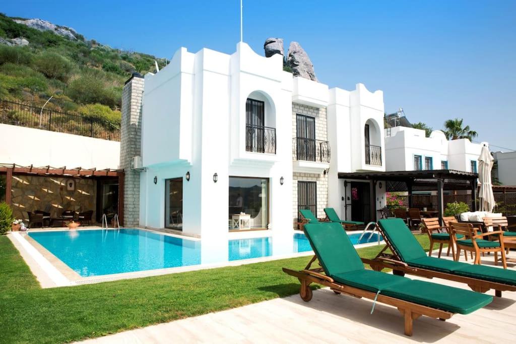 una villa con piscina e sedie a sdraio verdi di Villa Rana by Important Group Travel a Yalıkavak