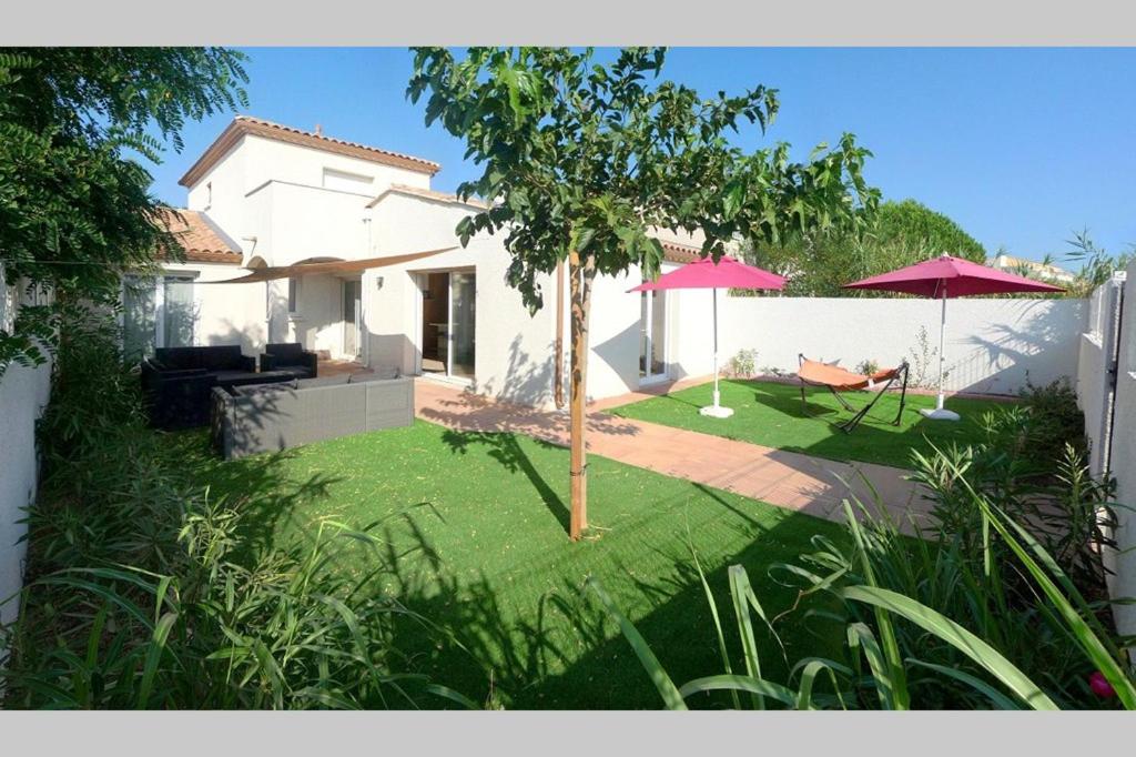 une maison avec une cour dotée de deux parasols dans l'établissement VILLA SECANTO Belle Villa Individuelle avec grand jardin Rochelongue Cap d'Agde, au Cap d'Agde