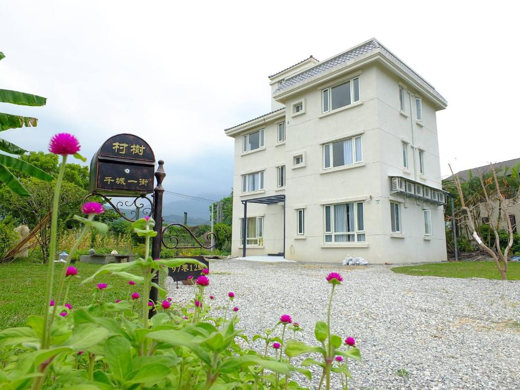 un edificio con un orologio e dei fiori davanti di Village Tree B&B a Ji'an