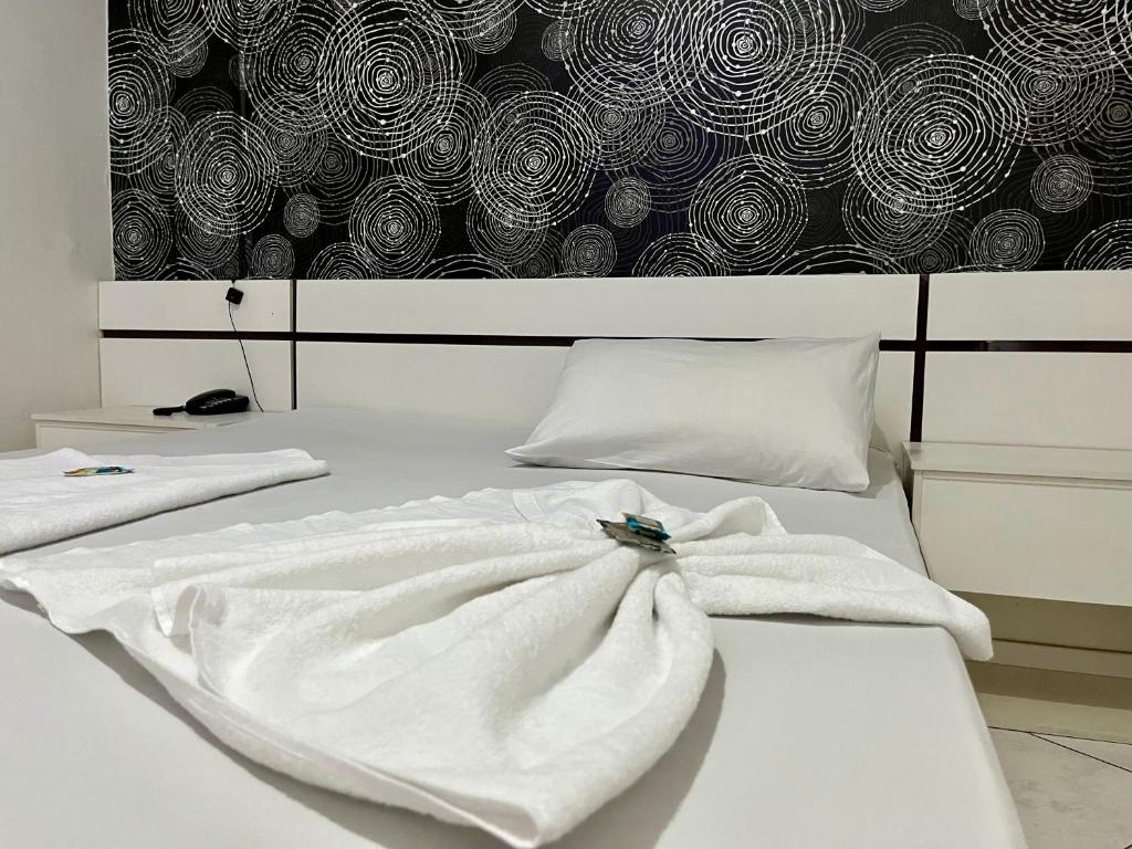 a bed with white towels on it with a wall at Hotel Sunshine in São Bernardo do Campo