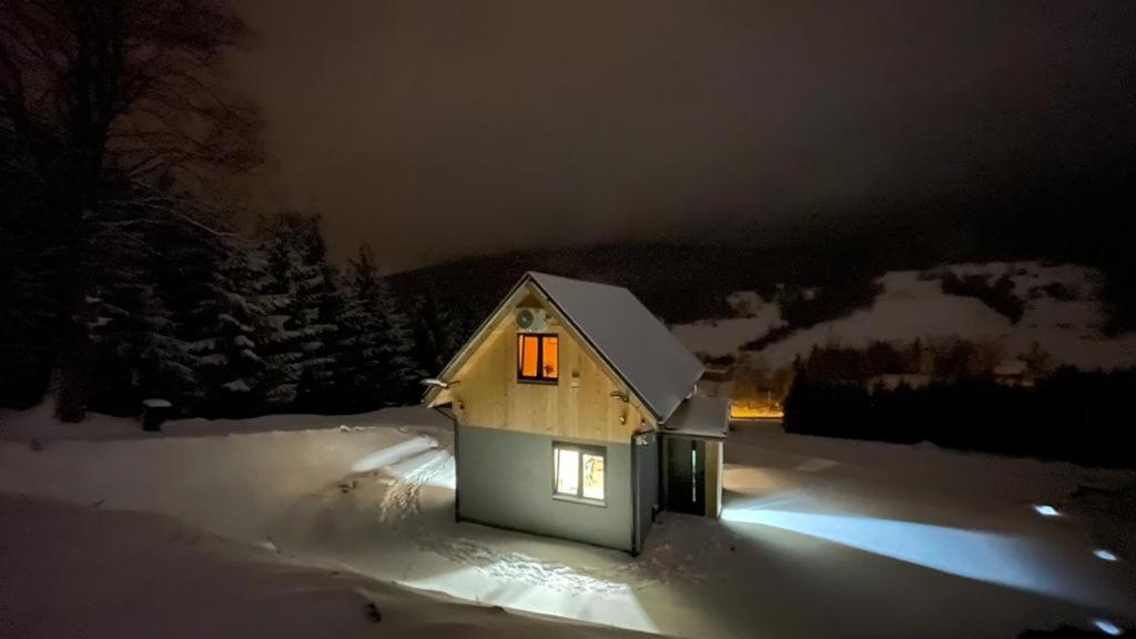 una pequeña casa en la nieve por la noche en DOMKI NA SKARPIE, en Rzeczka