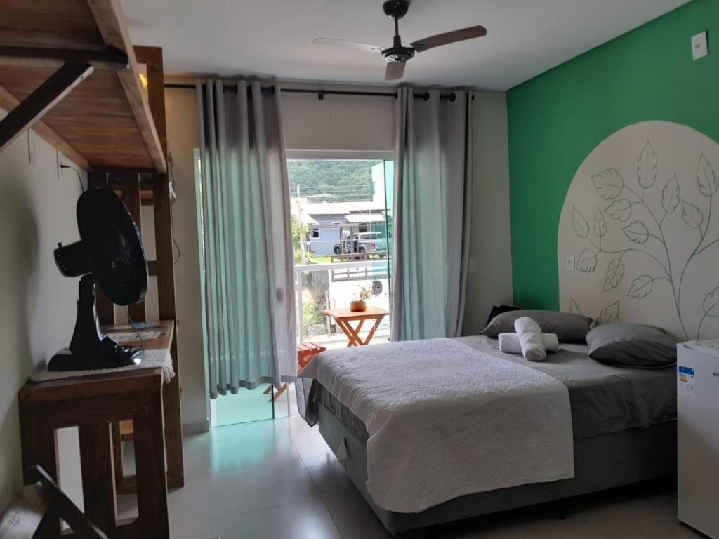 a bedroom with a bed and a green wall at Residencial Mãe terra in Bombinhas