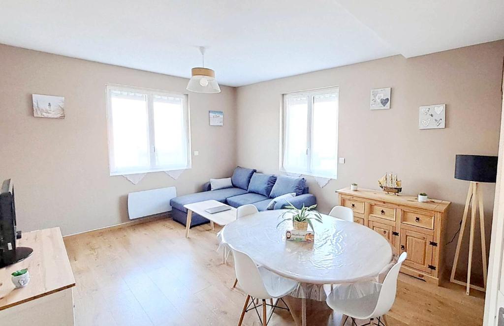 een woonkamer met een blauwe bank en een tafel bij Appartement 3 étoiles de 63m2 in Cabourg