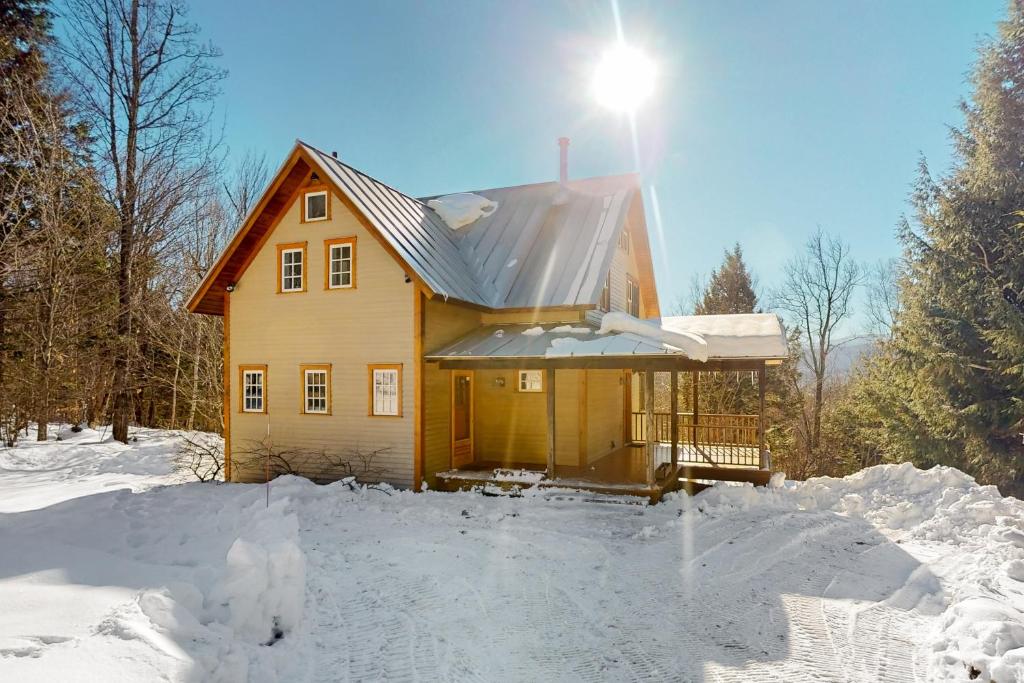 a house in the snow with the sun shining on it at Light-filled Retreat in Mad River Valley 