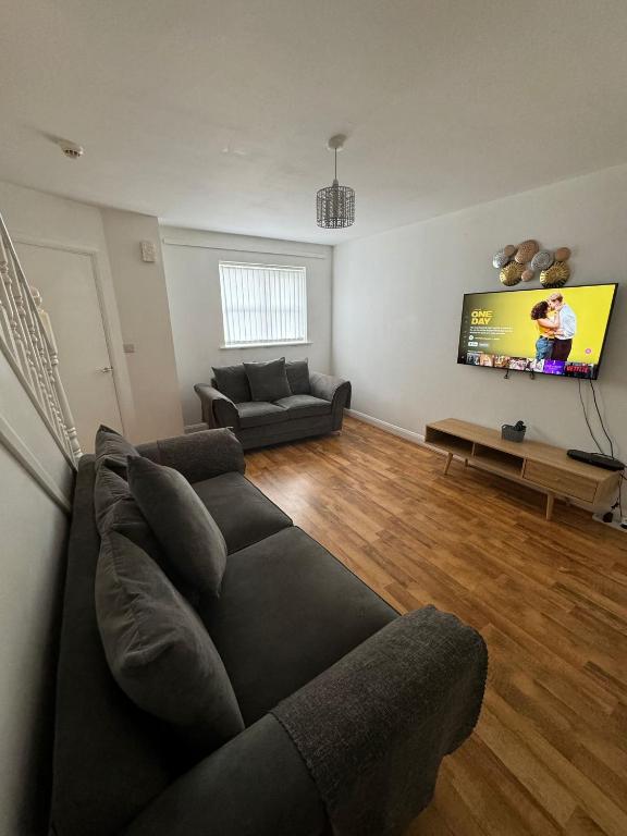 a living room with a couch and a flat screen tv at Manchester home near City Centre and City stadium in Manchester
