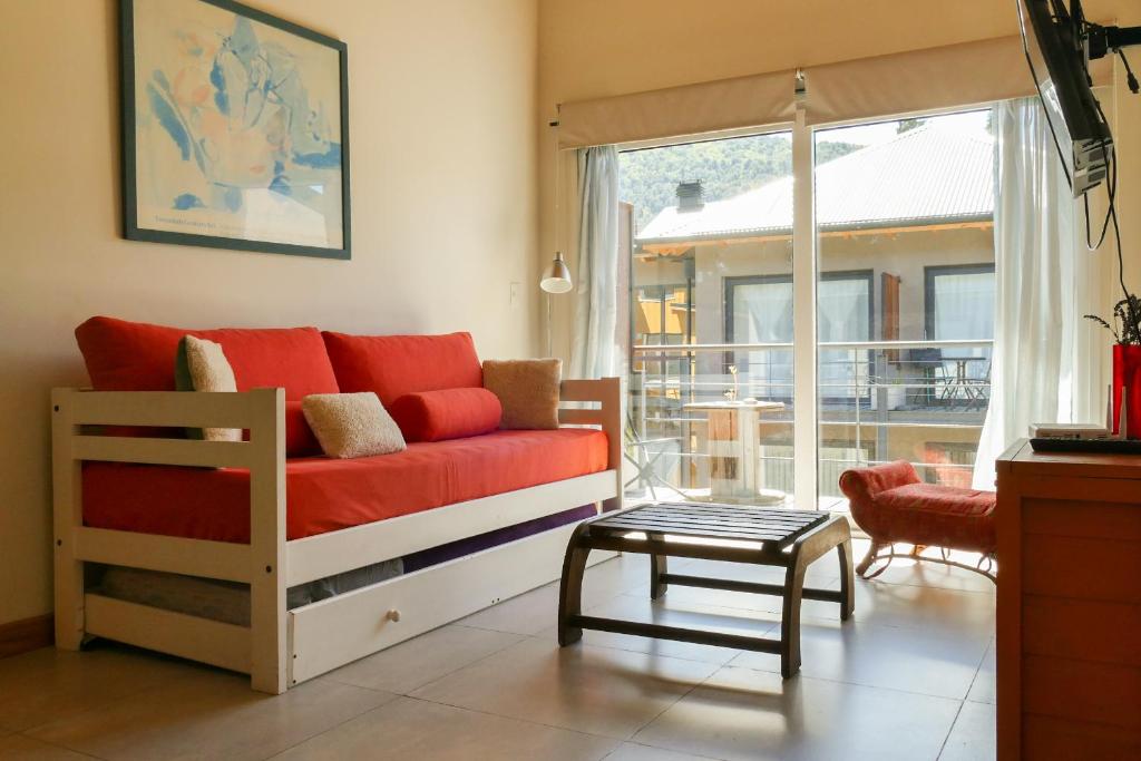 sala de estar con sofá rojo y mesa en Departamento Umain en San Martín de los Andes