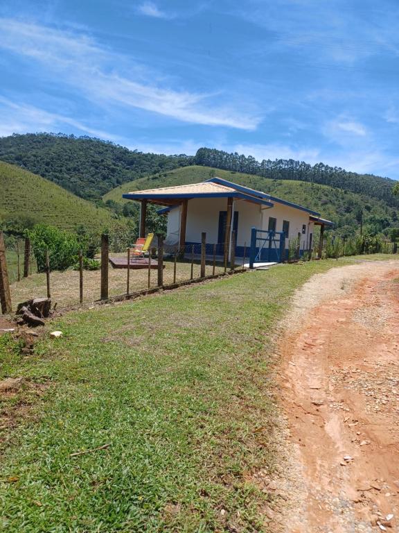 a house with a fence next to a dirt road at Chale Jatoba Monteiro Lobato in Monteiro Lobato