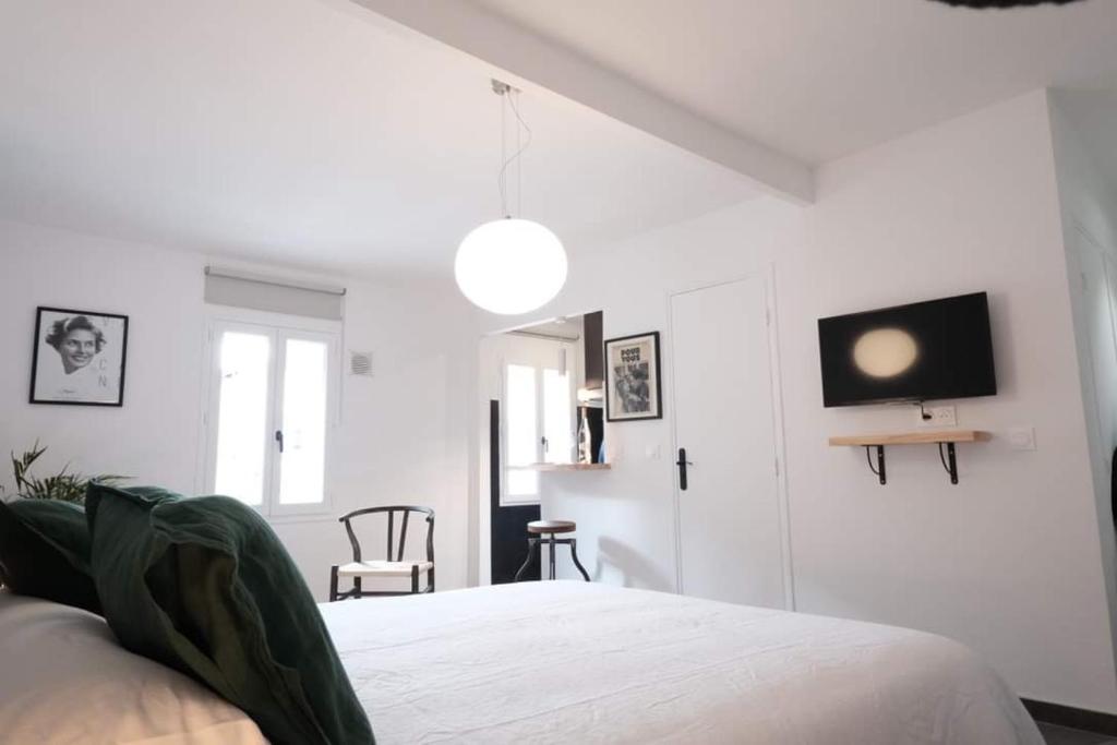 une chambre blanche avec un lit et une télévision au mur dans l'établissement Studio Cannes - 5mn Palais des Festivals (400m), à Cannes