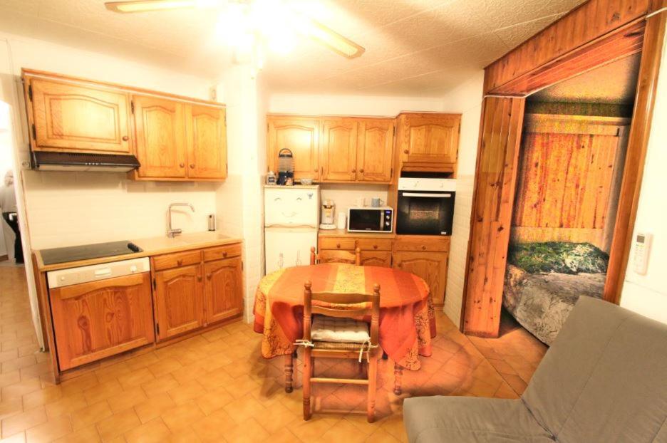 Il comprend une cuisine avec une table et des placards en bois. dans l'établissement St Aygulf Grand studio 400m de la plage, à Fréjus