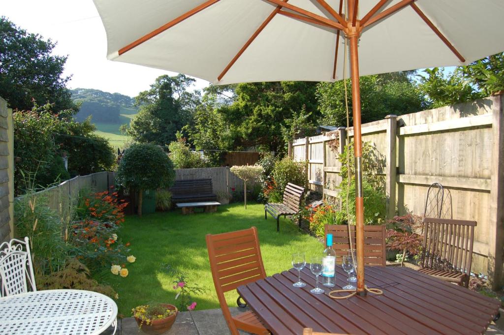 a wooden table with an umbrella in a backyard at Bronhaul Cottage in Pennal in Pennal