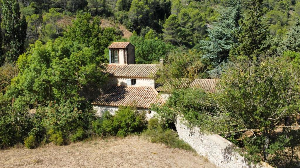 uma casa velha numa colina com árvores e arbustos em Le Moulin de La Grave - Lagrasse em Lagrasse