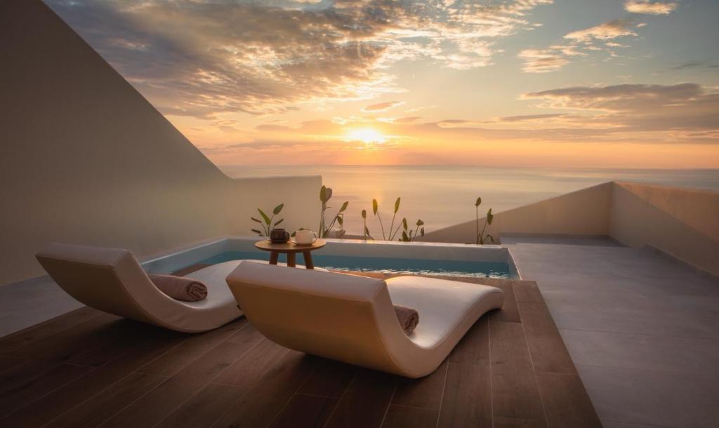 Pnoe Luxury Suites في فيرا: حمام به كرسيين بيض ومسبح