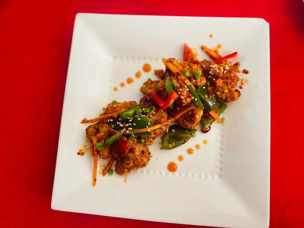 un plato blanco con comida en una mesa roja en NEW LAYA NEEM RESORT AND RESTAURANT en Dambulla