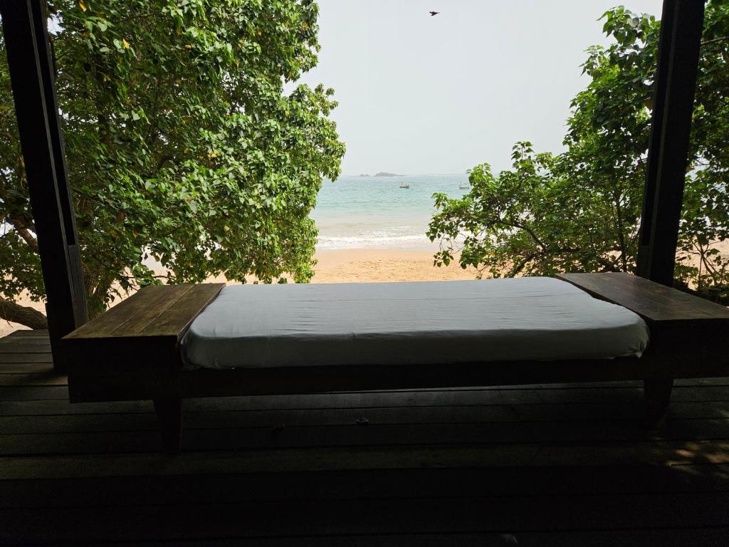 a bed on a porch with a view of the beach at Busua Beach House in Busua