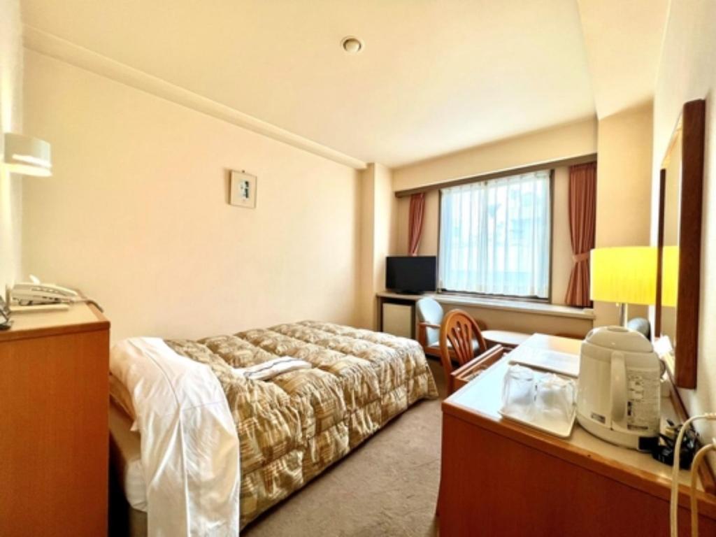 千葉市にあるHotel Tetora Makuhari Inagekaigan - Vacation STAY 90828vのベッドとデスクが備わるホテルルームです。