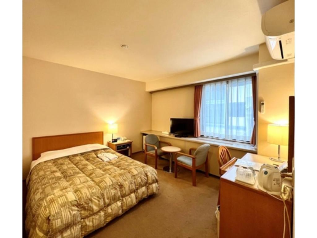 千葉市にあるHotel Tetora Makuhari Inagekaigan - Vacation STAY 91492vのベッドとデスクが備わるホテルルームです。