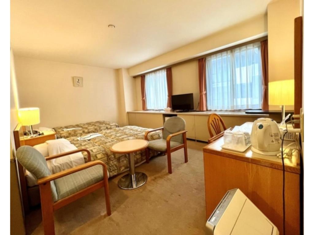 千葉市にあるHotel Tetora Makuhari Inagekaigan - Vacation STAY 91516vのベッド、デスク、椅子が備わるホテルルームです。