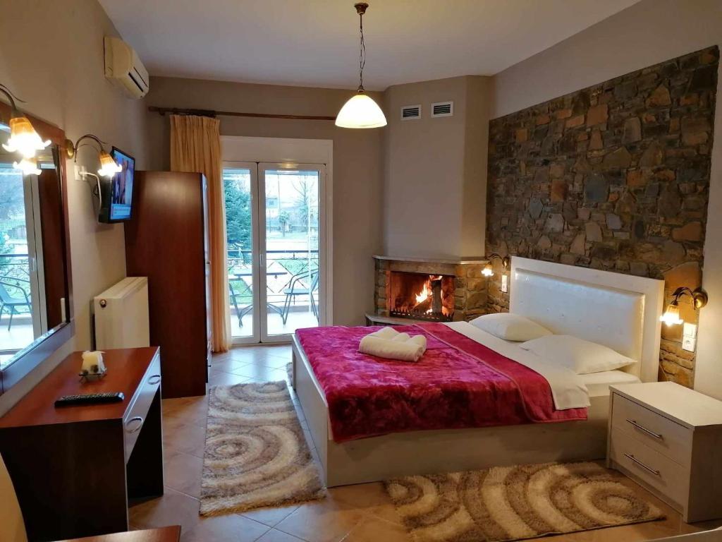 a bedroom with a large bed and a fireplace at ΥΑΚΙΝΘΟΣ in Kato Loutraki